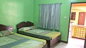 Une chambre avec deux lits, une fenêtre avec des rideaux et une porte donnant sur un espace extérieur.