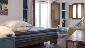Un dormitorio con cama, mesita de noche, silla, mesa y armario.