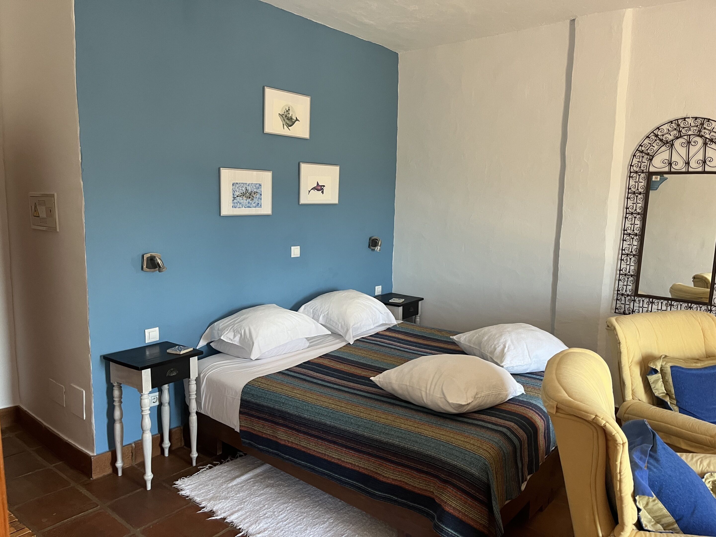 Una camera da letto con un letto, comodini, una sedia e opere d'arte appese al muro.