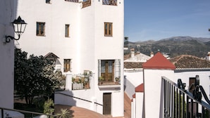 Un edificio blanco con varias ventanas, un balcón y un techo rojo.