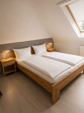 Ein Schlafzimmer mit einem Holzbett, zwei Nachttischen, einem Oberlicht und einer Heizung.