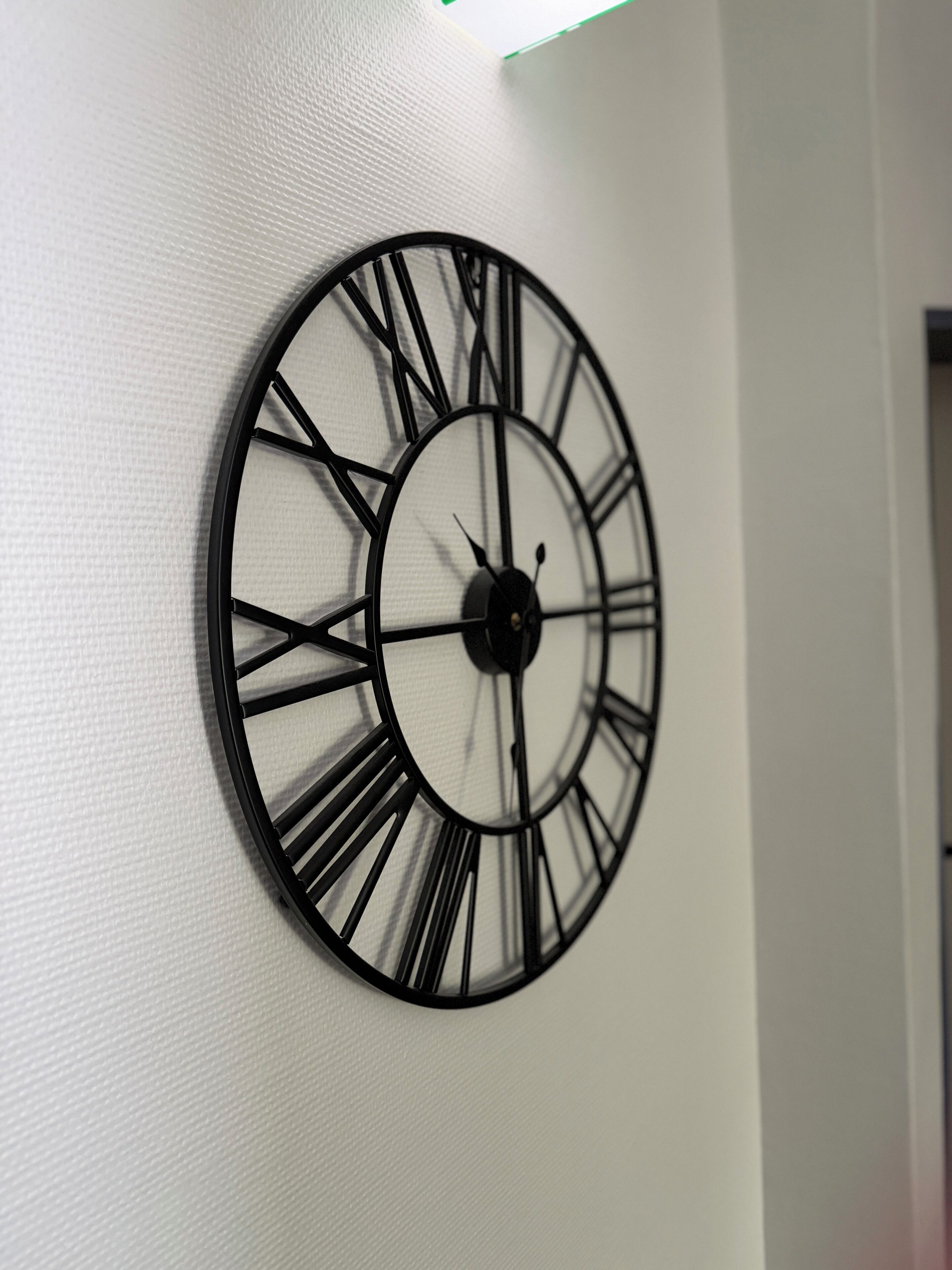 A wall-mounted clock with Roman numerals and a minimalist design.