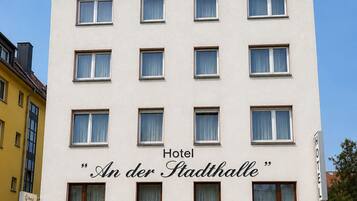 Un edificio de hotel con múltiples ventanas, un letrero que dice 'Hotel An der Stadthalle' y una base de ladrillo.