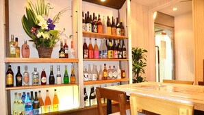 Zona de bar con estantes llenos de botellas de licor y una mesa con sillas.