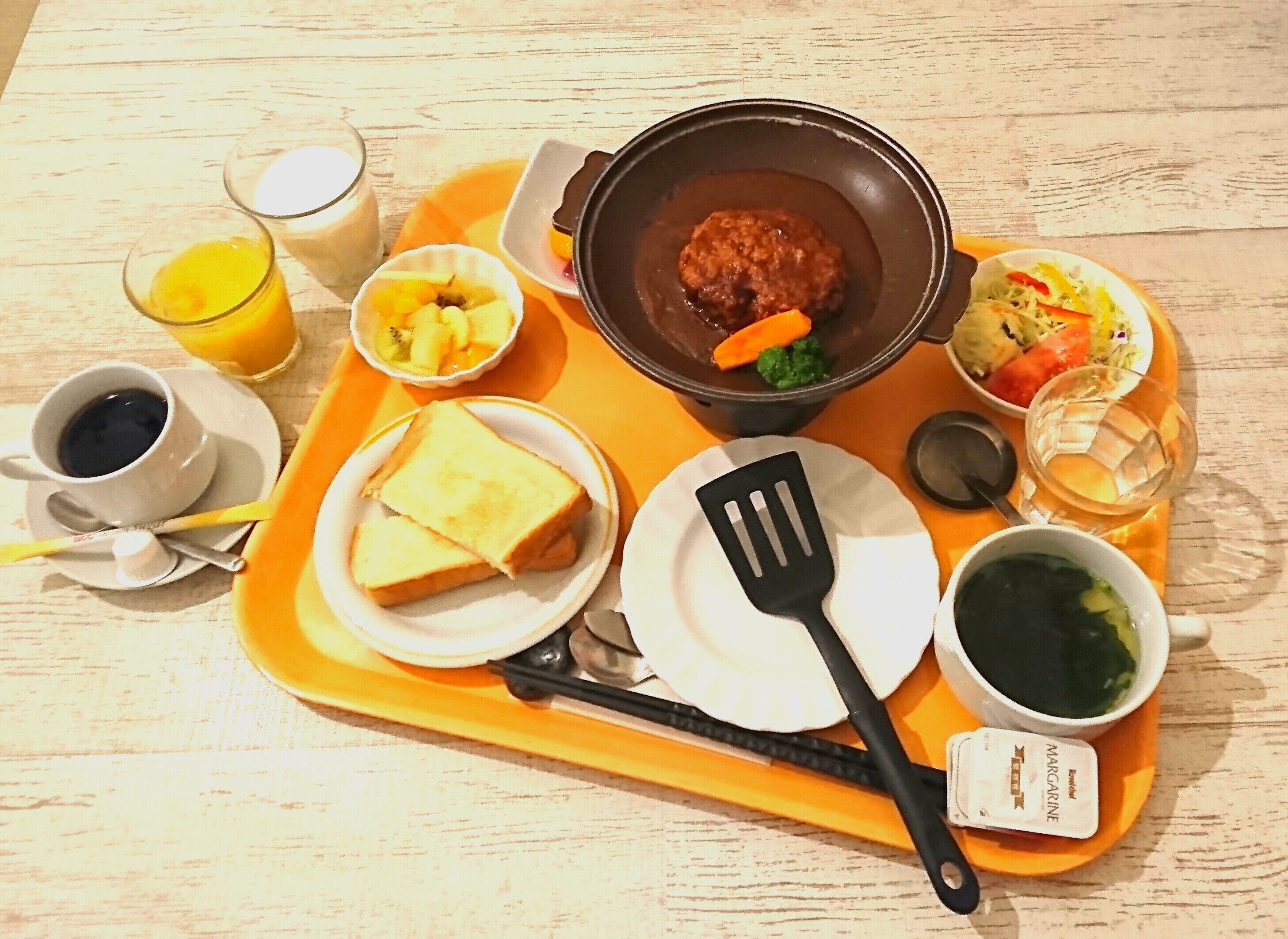 A tray with breakfast items including toast, a bowl of soup, a cup of coffee, and a glass of orange juice.