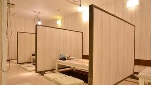 Una habitación con separadores de madera, una mesa con una silla y un pequeño mostrador con objetos encima.