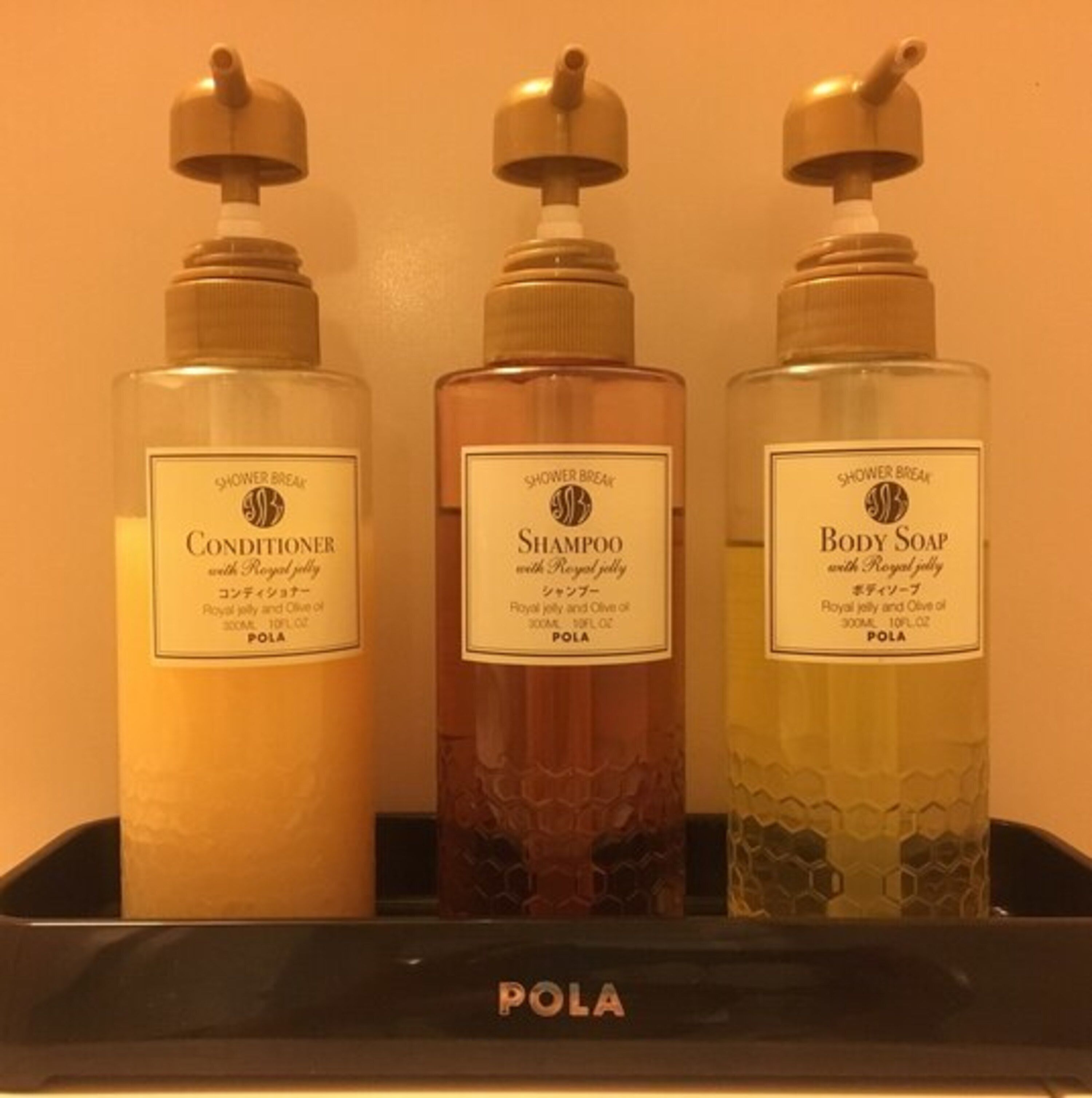Three bottles of shower products on a shelf labeled "POLA".