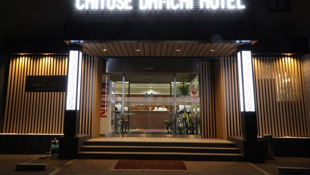 La entrada del Hotel Chitose Daiichi, con un diseño moderno, que muestra un mostrador de recepción y bicicletas afuera.