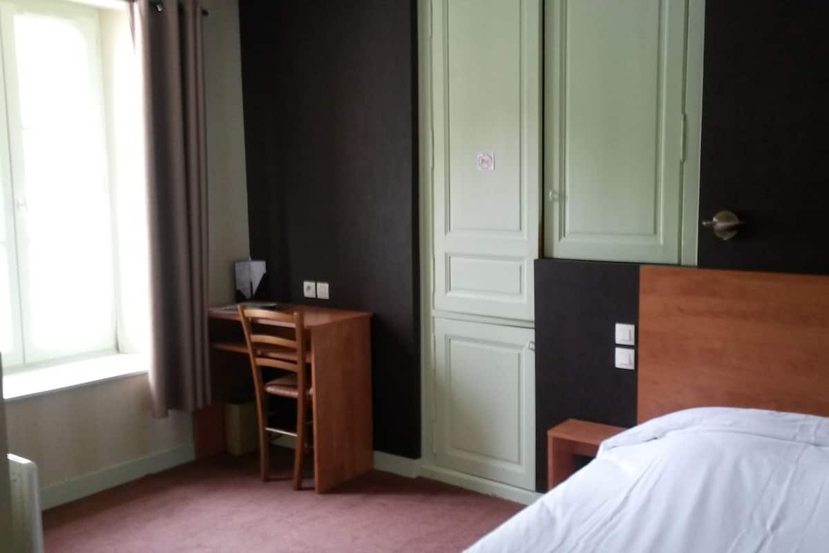 Een kamer met een bed, bureau en kledingkast.