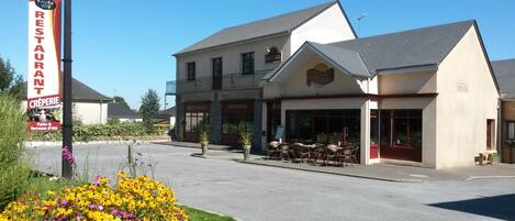 Un hotel con restaurante y una crepería, que cuenta con un balcón y terraza.