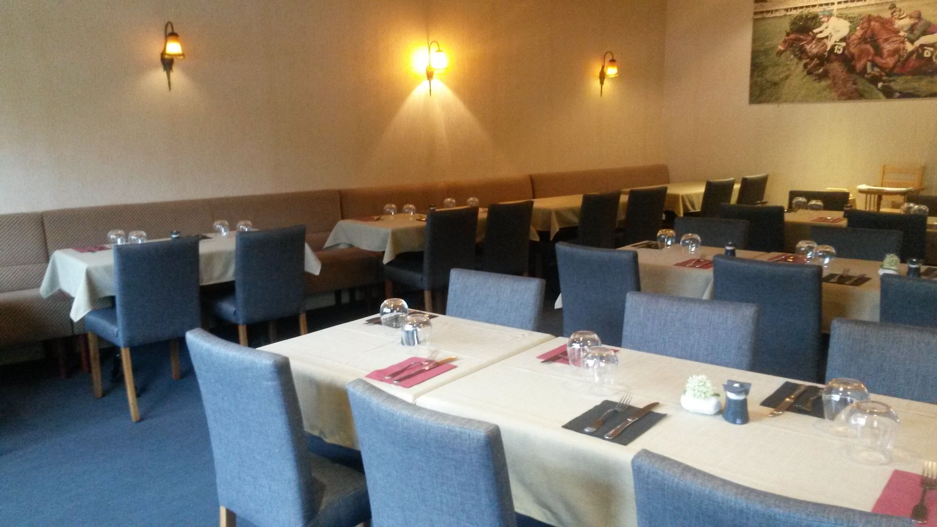 A dining area with tables set for multiple guests, each with cutlery and glasses.