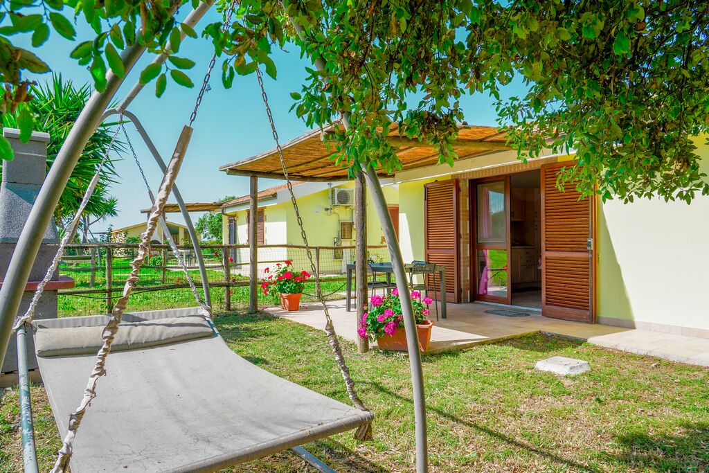 Propiedad residencial con un columpio, un porche cubierto y una casa con techo de tejas y contraventanas de madera.