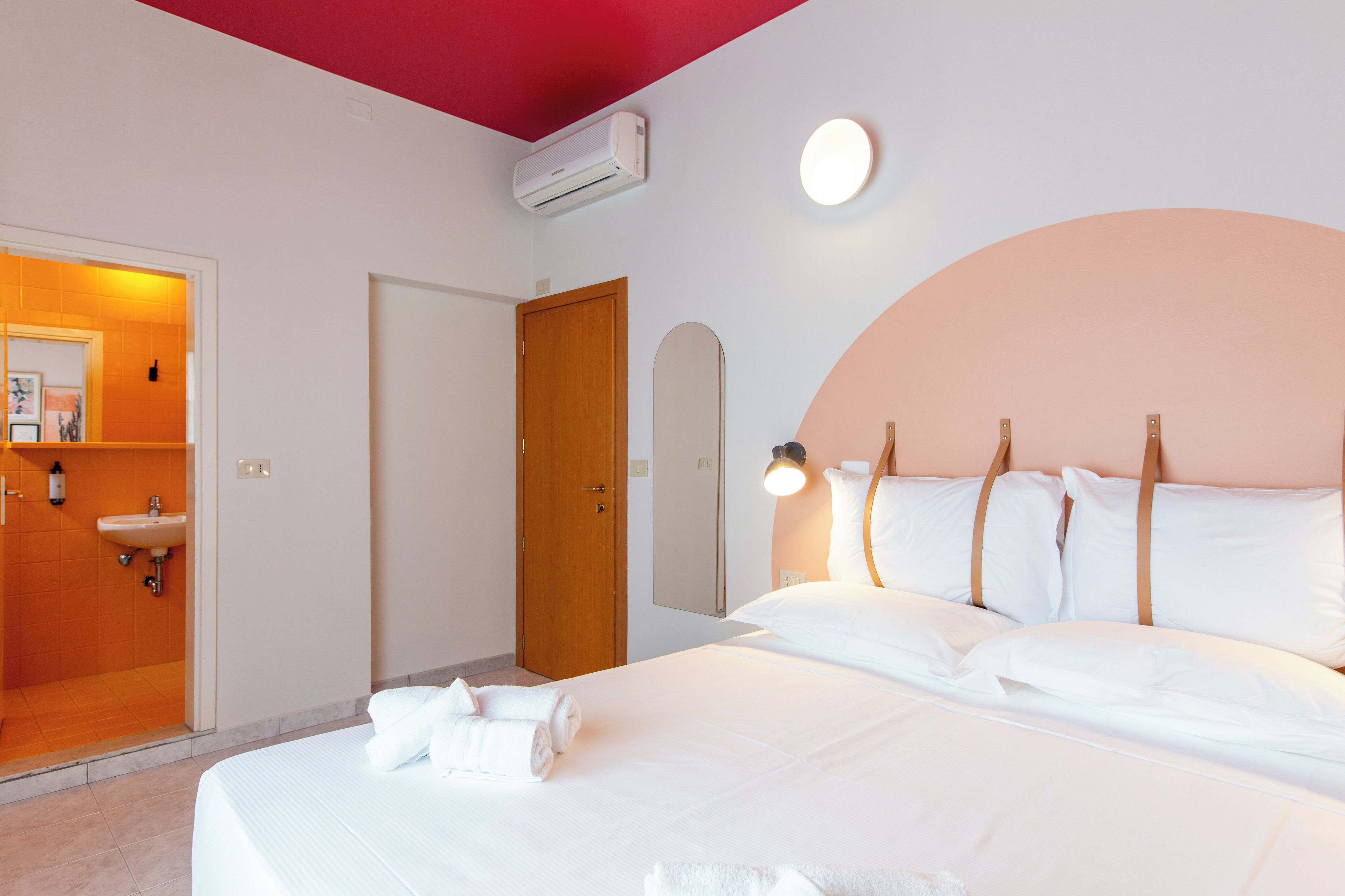 A hotel room with a bed, a bathroom with a sink, and a door.