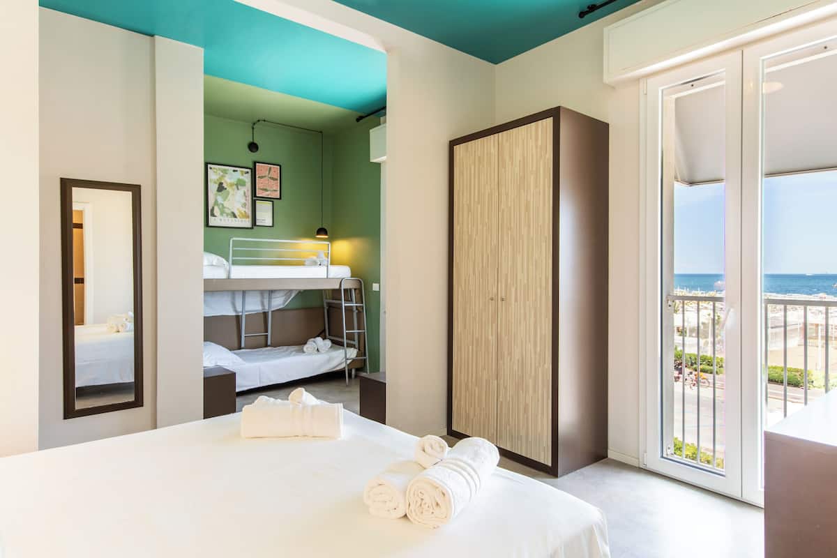 A hotel room with a bunk bed, a large wardrobe, and a balcony with a view.