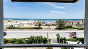 A beach view from a window overlooking a parking lot and beach area with umbrellas and beach chairs. - Hotel Belvedere Rimini (Rimini)