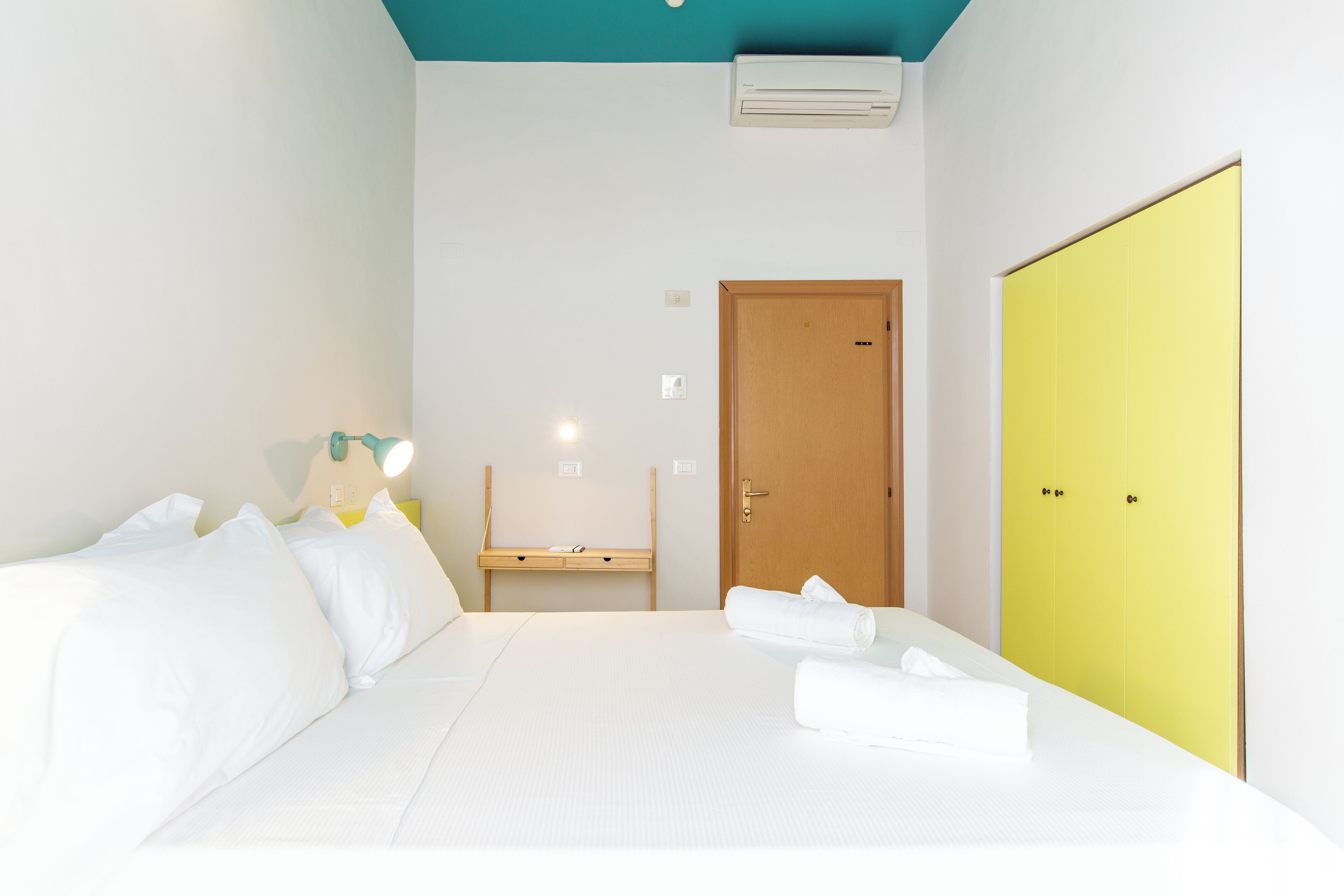 Una habitación de hotel con una cama, un escritorio y un armario.