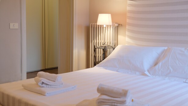 Une chambre d’hôtel avec un lit bien fait, une lampe et un radiateur.