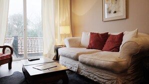 Un salon avec un canapé, une table basse, une lampe et une œuvre d’art encadrée accrochée au mur.