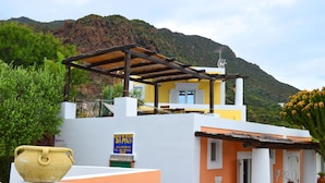 A building with a yellow and white facade, a pergola, and a sign for 'DA PINA'. - Casa Ambra (Lipari)