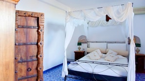A bedroom with a four-poster bed, a wooden wardrobe, and patterned floor tiles. - Casa Ambra (Lipari)