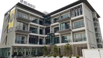 Un hotel de varios pisos con un diseño moderno, que cuenta con balcones en cada planta y ventanas amplias.