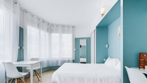 Quarto de hotel moderno com cama, escrivaninha e cadeira.