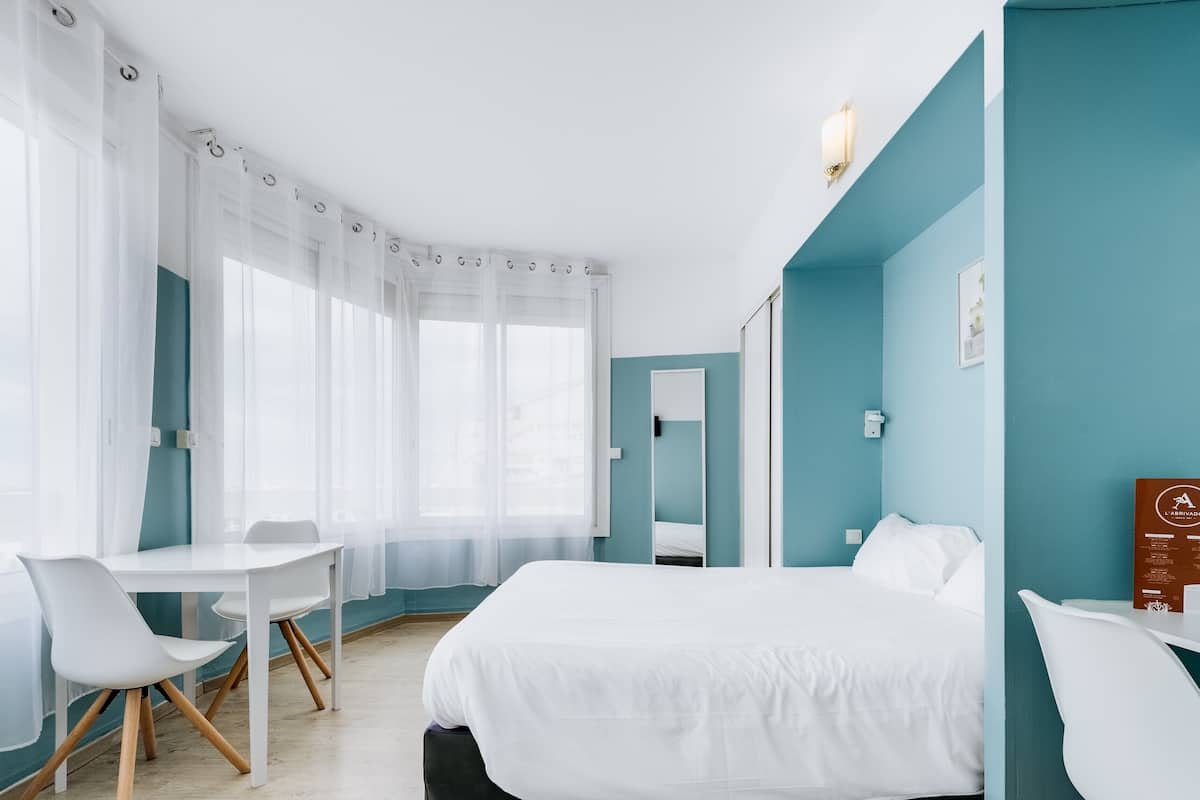 A modern hotel room with a bed, a desk, and a chair.