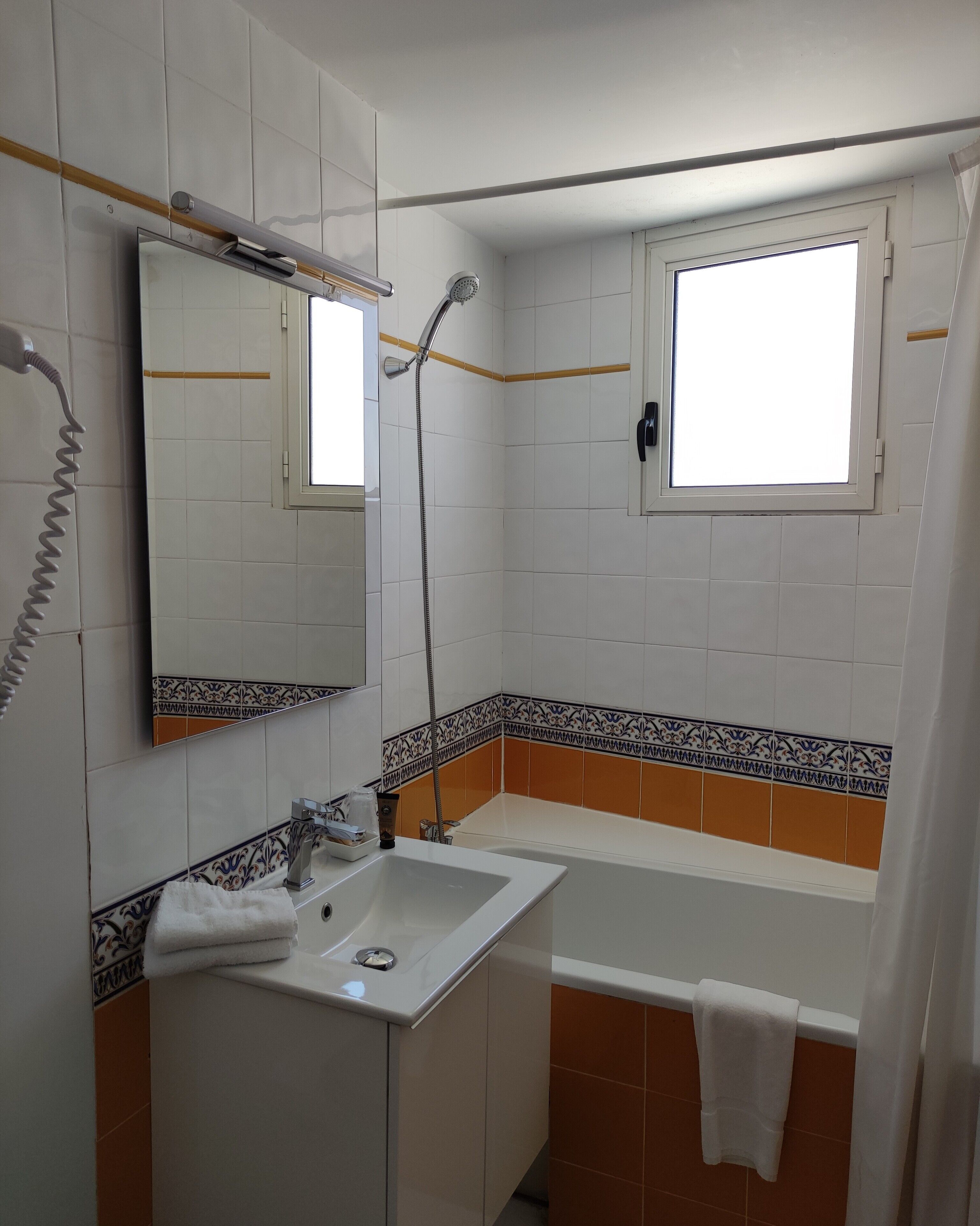 Un baño con lavamanos, espejo, ducha y ventana.