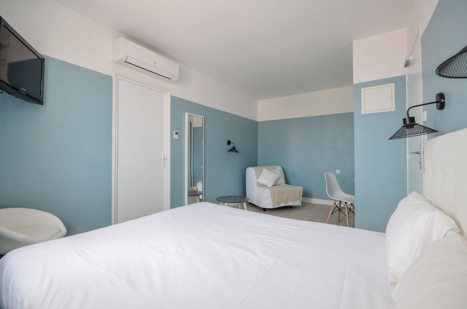 Une chambre à coucher avec un lit, une chaise, un bureau et un téléviseur.