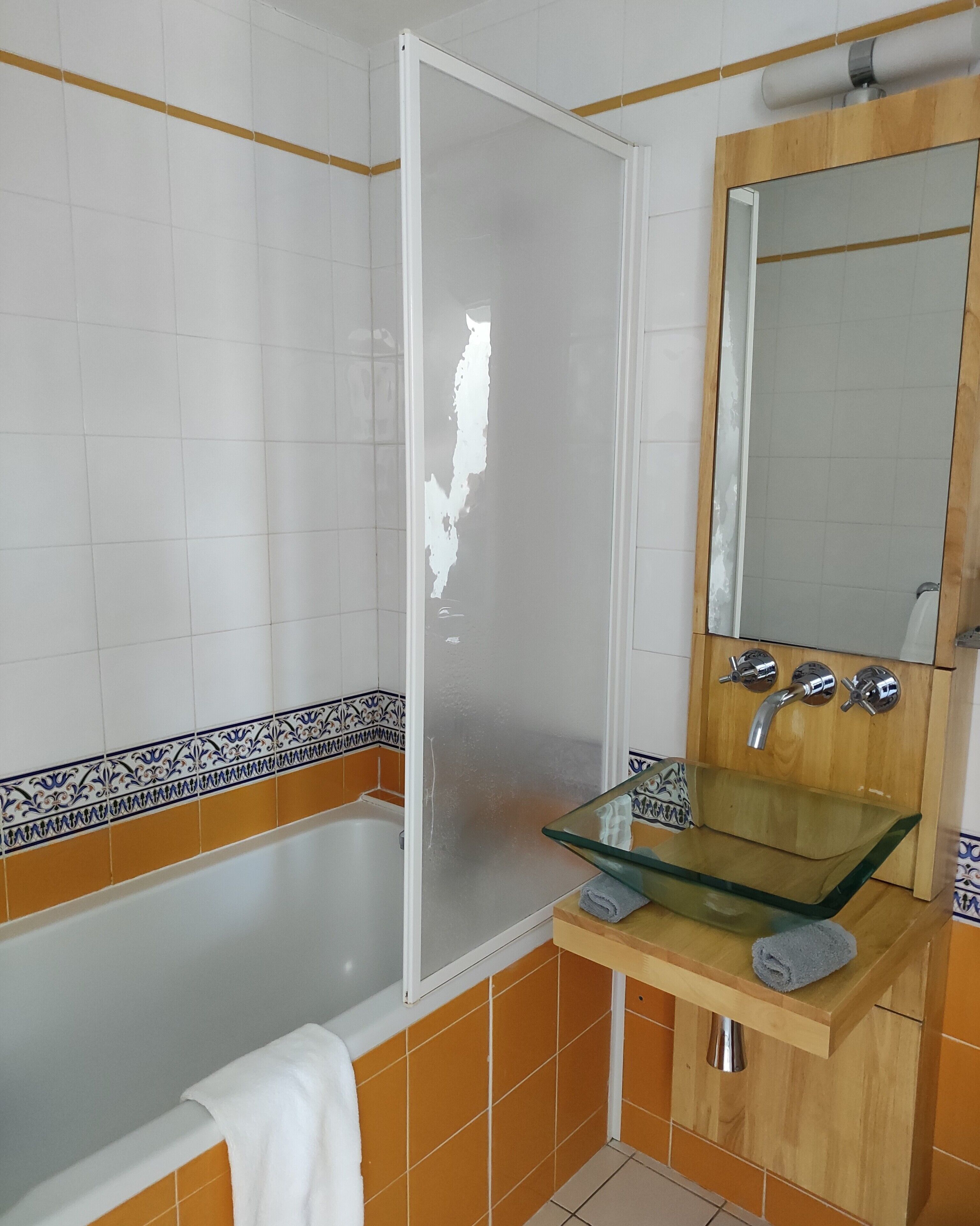 A bathroom with a glass sink, a mirror, and a bathtub.