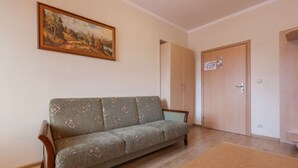A living room with a sofa, a painting on the wall, and a door with a sign. - Antica Residence (Kraków)