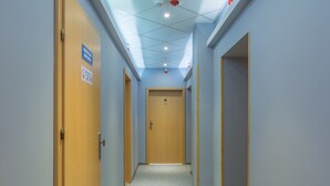 A hallway with wooden doors, a ceiling with recessed lighting, and a sign indicating a fire exit. - Antica Residence (Kraków)