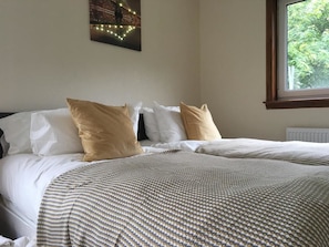 A bed with white and beige bedding, a patterned blanket, and a wall-mounted picture. - Majesty Tweed Apartment (Dundee)