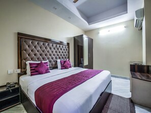 A hotel room with a large bed, a wardrobe, a desk, and a mirror. - OYO 2807 Hotel Crosswinds Residency (Noida)