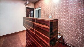 A reception desk with a modern design, a ceiling fan, and a textured wall. - OYO 2807 Hotel Crosswinds Residency (Noida)