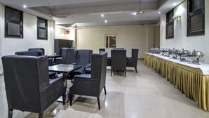 A conference room with a long table, several chairs, ceiling fans, and a buffet setup. - OYO 2807 Hotel Crosswinds Residency (Noida)