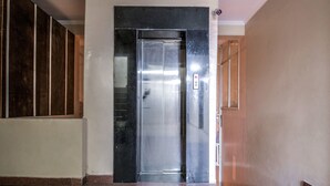 A modern elevator with a metallic finish, a marble-topped corridor, and a wooden door frame. - OYO 2807 Hotel Crosswinds Residency (Noida)