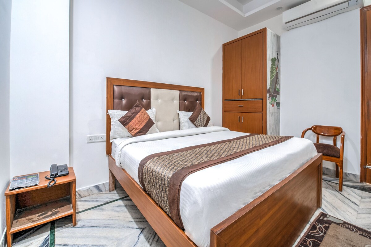 A neatly arranged bedroom with a wooden bed, a small bedside table, a wardrobe, and a chair.