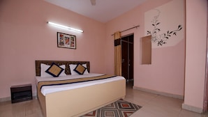 A bedroom with a bed, a nightstand, a mirror, and a wall decoration. - OYO 8907 The Nest (Greater Noida)
