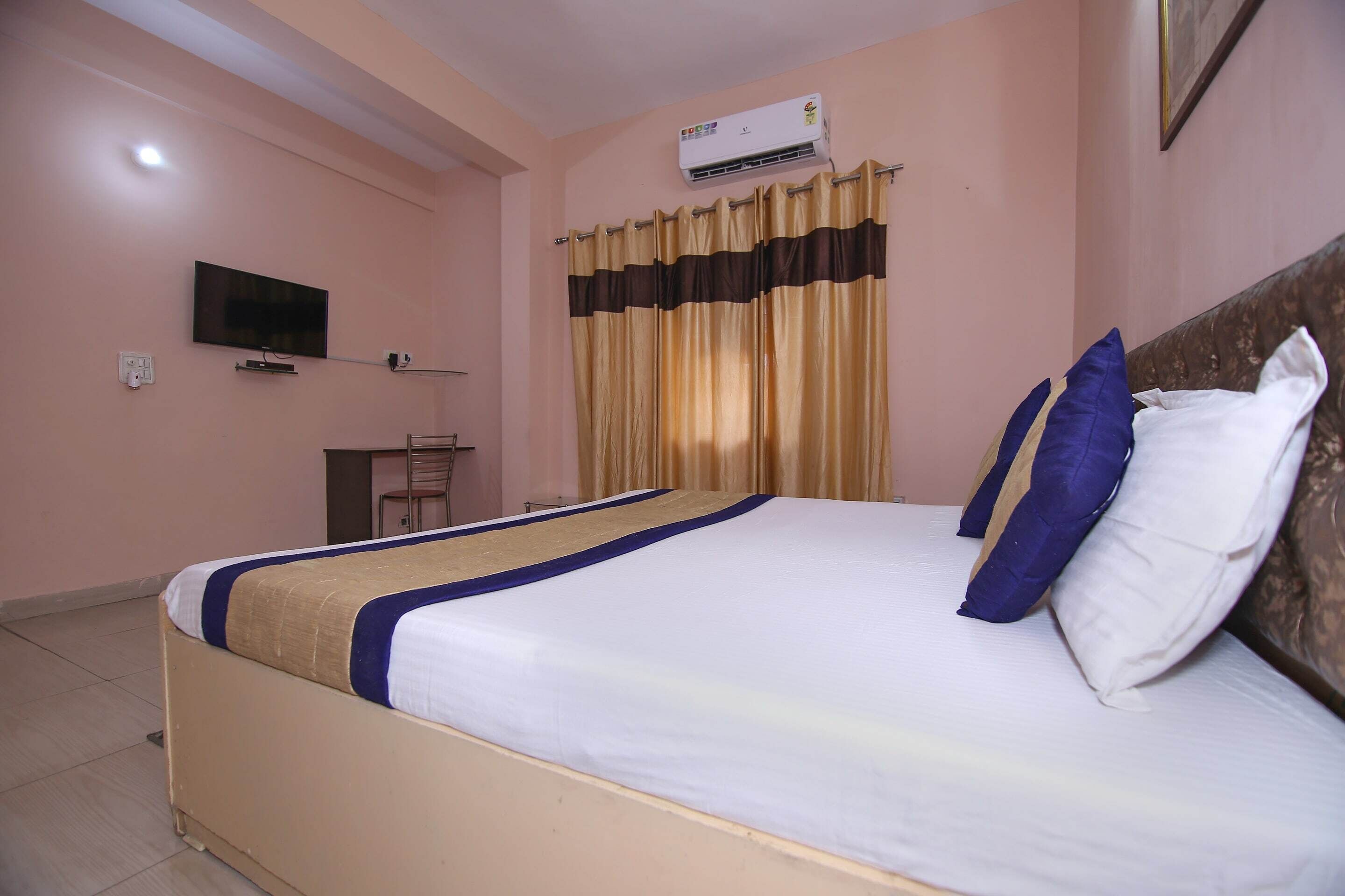 A hotel room with a bed, a television, an air conditioner, and curtains.