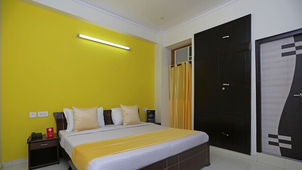 A hotel room with a bed, a nightstand, a wardrobe, and a bathroom with a shower curtain. - OYO 9339 Terrene Empire (Noida)