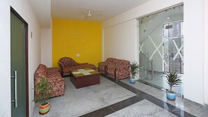 A lobby with two sofas, a coffee table, and potted plants. - OYO 9339 Terrene Empire (Noida)