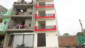A multi-story building with balconies, a closed shuttered door, and parked motorcycles. - OYO 9339 Terrene Empire (Noida)