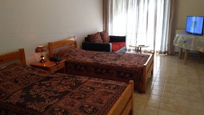 Habitación de hotel con dos camas, una mesita, un sofá y un televisor.