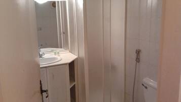 A small, compact bathroom with a sink, mirror, and toilet.