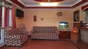 A living room with a sofa, a fish tank, and a television. - OYO 10661 DSR Classic (Noida)