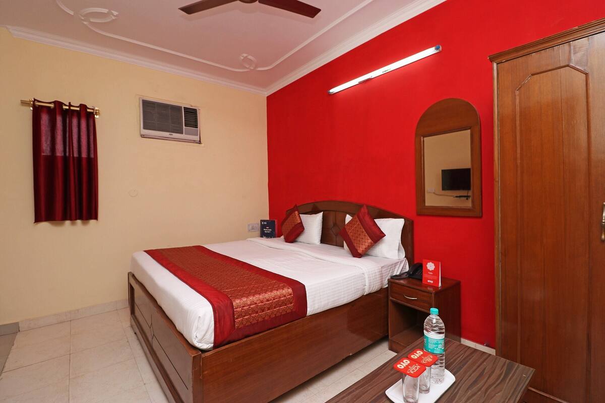 A hotel room with a bed, a nightstand, a mirror, a wardrobe, and a ceiling fan.