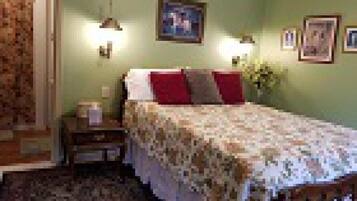 A bedroom with a bed, nightstand, wall-mounted lamps, and framed pictures.