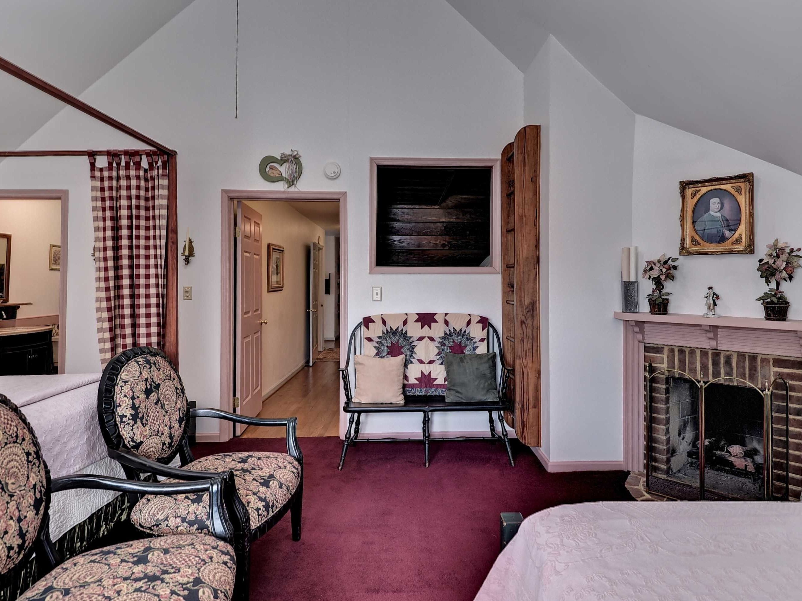 A room with a fireplace, a bed, a chair, and a desk.