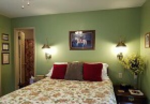 A bedroom with a bed, a nightstand, a lamp, and a framed picture on the wall. - Aldrich House Bed & Breakfast (Williamsburg)